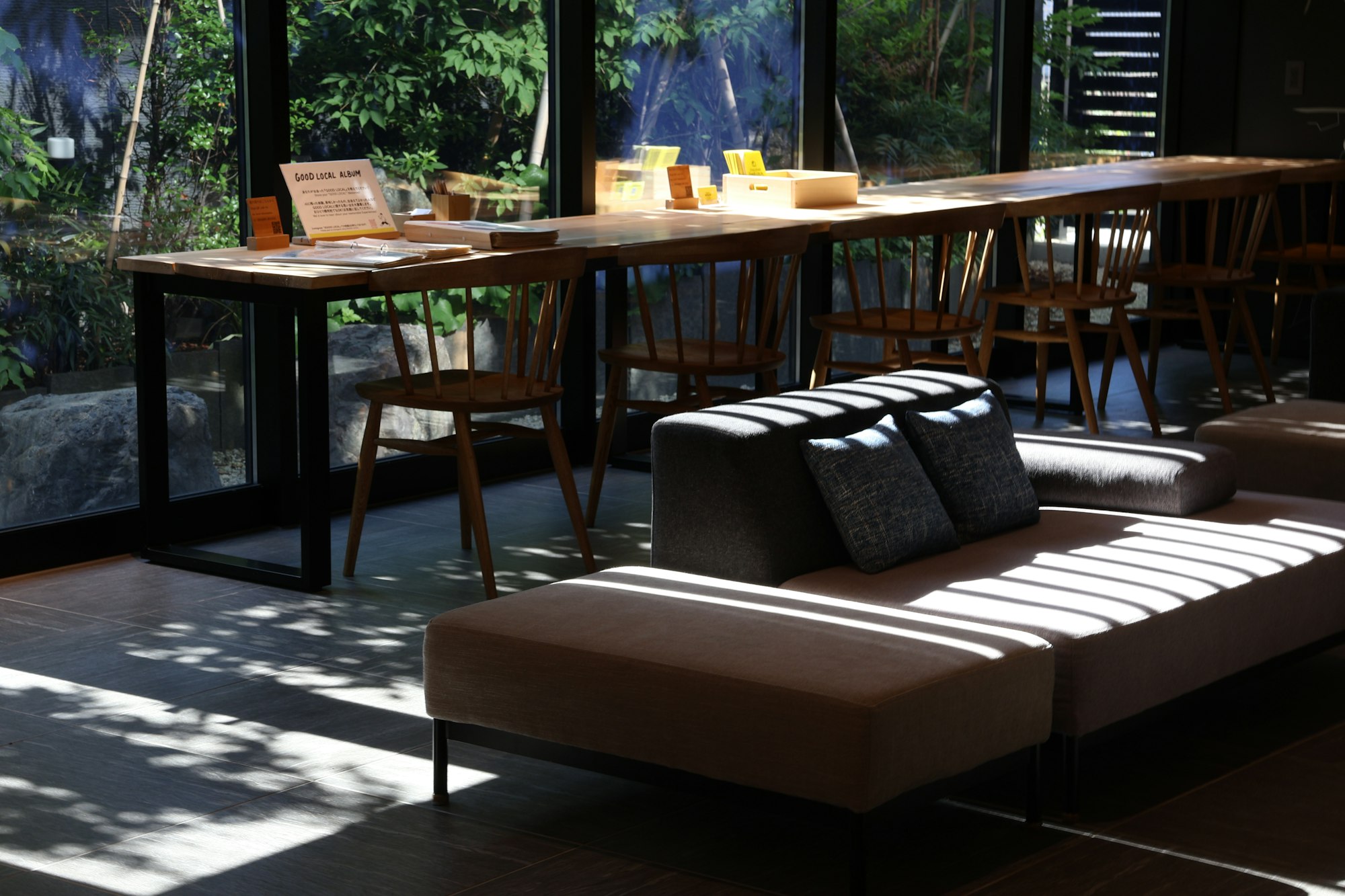 Sala de trabajo con mesa larga de madera frente a un ventanal al bosque